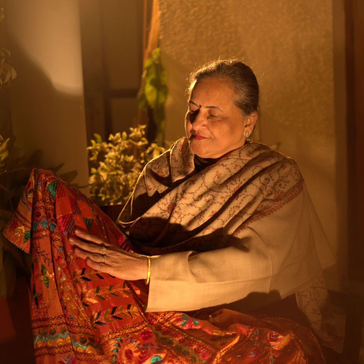 Older woman holding embroidered Phulkari fabric